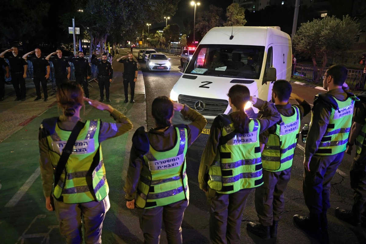 Policías israelíes saludan hacia el vehículo que transporta los cuerpos de cuatro rehenes entregados por Hamas y que llegan al Centro Nacional de Medicina Forense de Tel Aviv, el 15 de octubre de 2025. Foto 