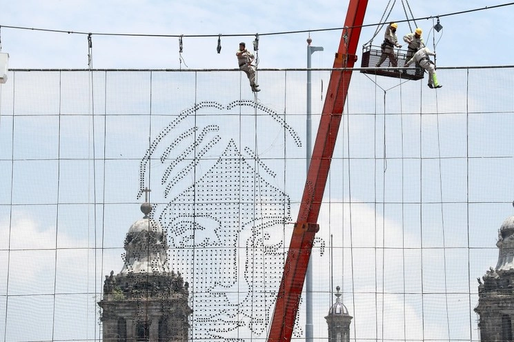 Trabajadores del gobierno capitalino colocan en el Zócalo la luminaria con las imágenes de los héroes patrios. Foto María Luisa Severiano