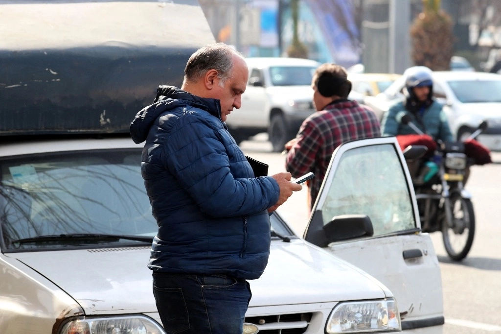 Un iraní mira las noticias en su teléfono en Teherán, sobre los ataques paquistaníes. Foto Afp