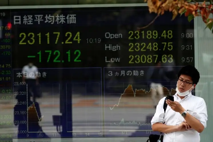 Un transeúnte en Tokio frente a una pantalla que muestra el índice bursátil Nikkei en imagen de archivo. Foto Ap 