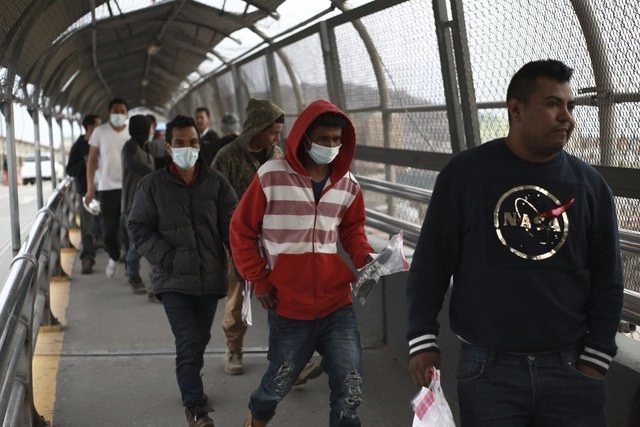 Migrantes con cubrebocas en el puente internacional que une Ciudad Juárez, en México, y El Paso, en EU, en imagen del 21 de marzo pasado. Foto Ap

