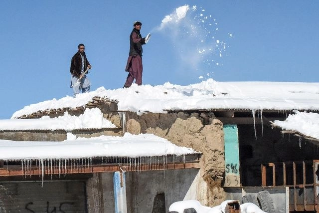 Trabajadores remueven nieve del techo de un hotel en Queta, Afganistán. Foto Afp