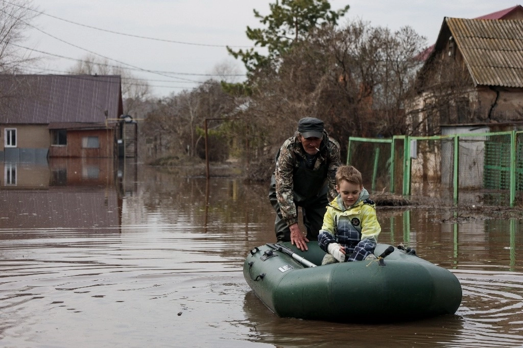 Un hombre empuja a un bote con un niño en un área inundada de Orenburg, Rusia. Foto Ap 
