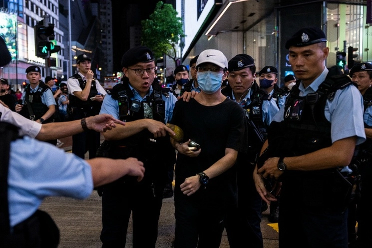 Un miembro del público es escoltado por la policía después de encender la luz de un teléfono inteligente cerca de Victoria Park, el antiguo lugar de la ciudad para la vigilia anual de la masacre de Tiananmen de 1989, en Hong Kong, el 4 de junio de 2023. Foto Ap