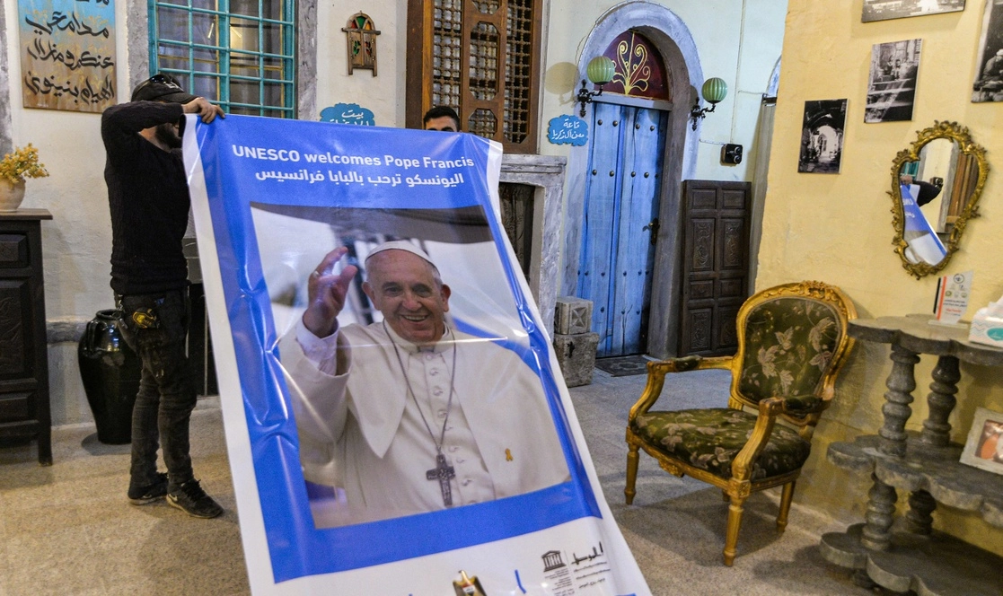 Hombres sostienen un cartel de la UNESCO que da la bienvenida al Papa Francisco en un centro cultural en la ciudad vieja de Mosul, en el norte de Irak (anteriormente devastada por militantes del grupo Estado Islámico). Foto Afp