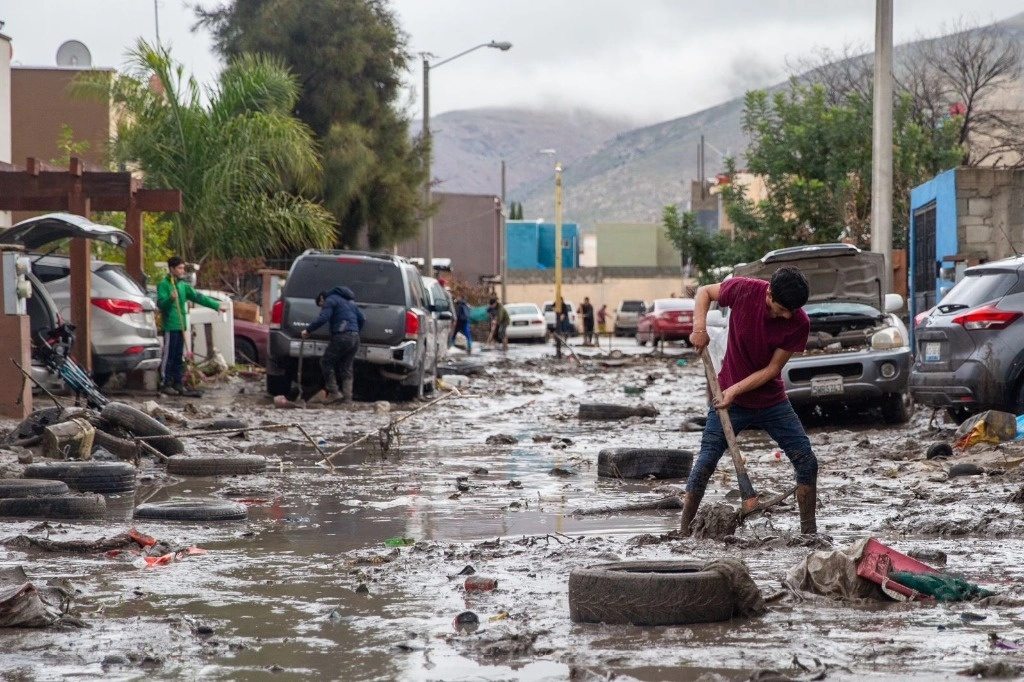 Con el agua arriba de la cintura, vecinos de la privada Cedros, del fraccionamiento Ribera del Bosque, tuvieron que derribar una barda para dejar correr el agua que tenía inundadas sus casas. Foto Luis Bautista / La Jornada Baja California