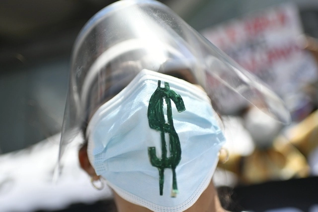 Durante una protesta en el Día del Trabajo, una trabajadora de la salud de Venezuela usa un cubrebocas con el signo de dólar. Foto Ap