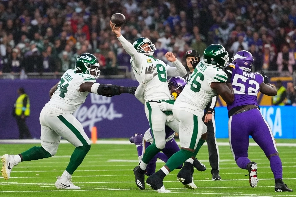 El quarterback de los New York Jets, Aaron Rodgers (8), segundo desde la izquierda, lanza bajo presión durante la segunda mitad de un partido de fútbol americano de la NFL contra los Minnesota Vikings, el 6 de octubre de 2024, en el estadio Tottenham Hotspur en Londres. Foto Ap