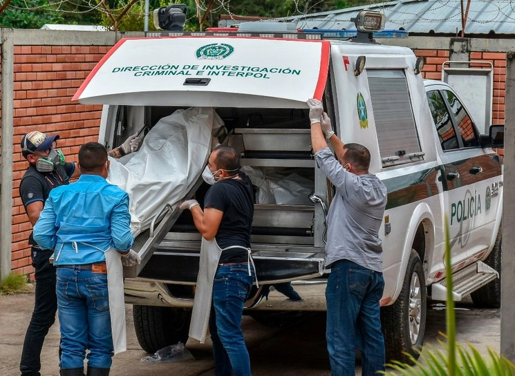 Policías recogen los cuerpos de víctimas de una masacre presuntamente a manos de grupos armados en el municipio colombiano de Arauca, el 22 de agosto. Foto Afp