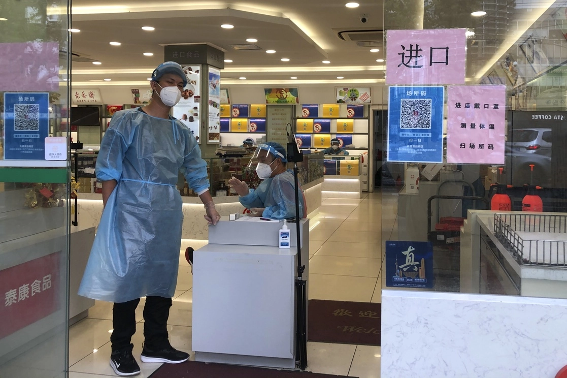 El gobierno chino ordenó a los residentes de partes de Shanghai y Pekín que se sometan a más rondas de pruebas de covid-19 luego del descubrimiento de nuevos casos en las dos urbes, mientras que se mantienen estrictas restricciones en Hong Kong, Macao y otras ciudades. En la imagen, trabajadores vigilan la entrada a una tienda de autoservicio en Shanghai, el 6 de julio de 2022. Foto Ap
