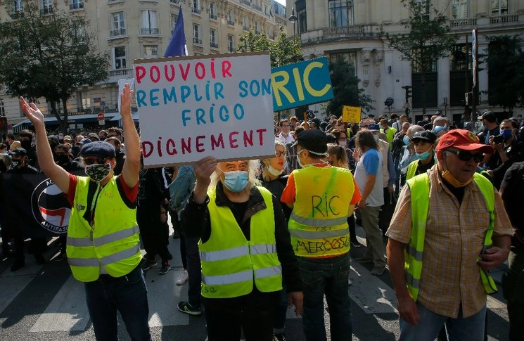 Un hombre sostiene un cartel que dice "poder llenar la nevera con dignidad" durante una protesta por la justicia social en París.Foto Ap