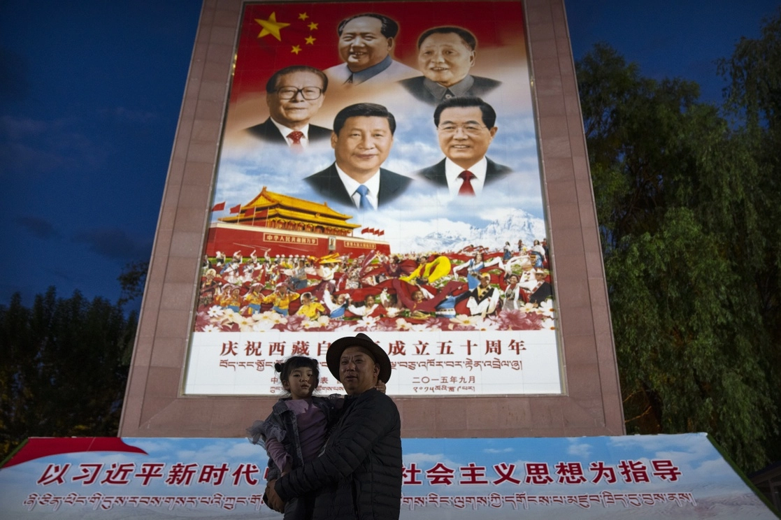 Un hombre y una menor posan frente a un mural con la imagen del presidente chino, Xi Jinping (en la parte inferior central), y otros líderes, en una plaza pública del Palacio Potala, en Lhasa. Foto Ap / Archivo