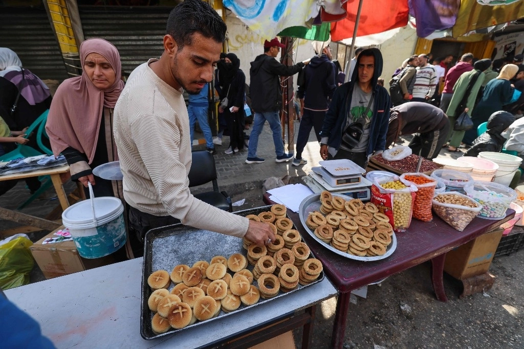 Un panadero palestino vende galletas tradicionales en una calle de Rafah, al sur de Gaza, en el fin del mes de ayuno del Ramadán. Foto Afp 